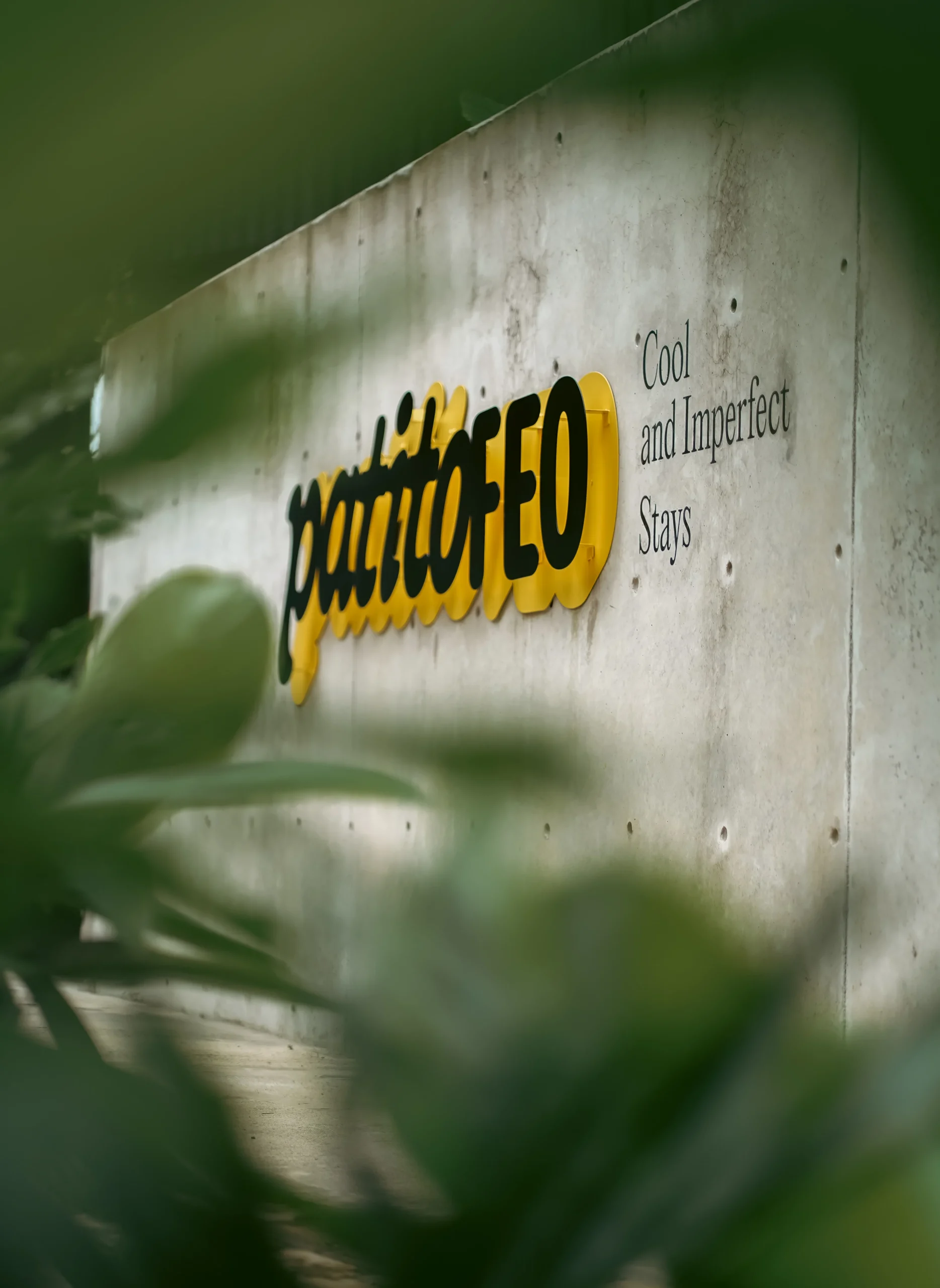 Letrero de hormigón gris con la palabra “Patiofeo” en letras amarillas – señalización urbana de marca registrada por Suma Estudios