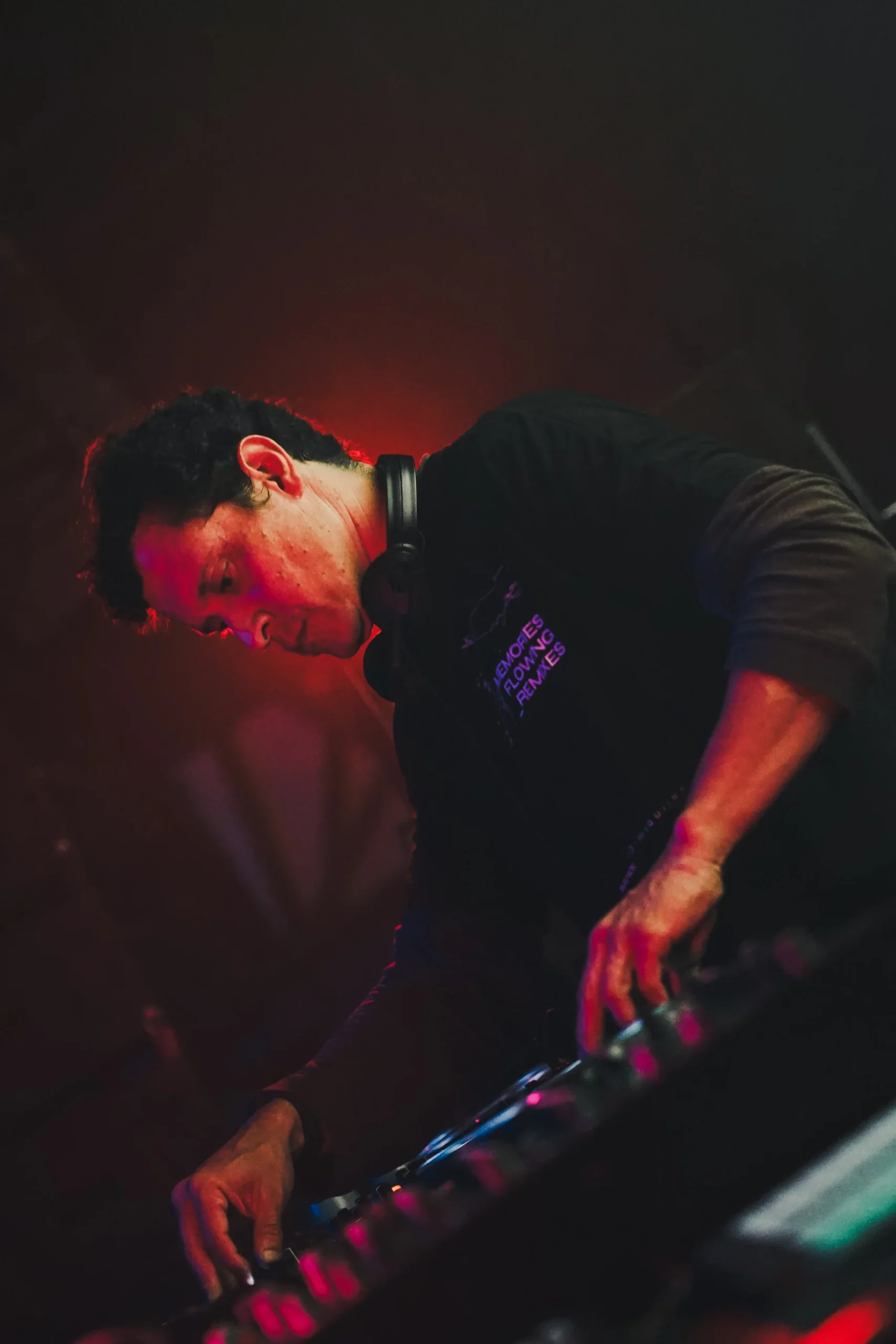 DJ Julio Victoria tocando en evento en Manizales con fondo negro y luces rojas – fotografía documental de música electrónica por Suma Estudios